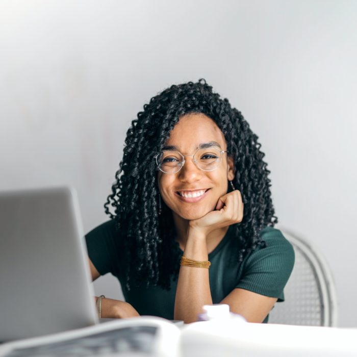 woman in green shirt and glasses in front of laptop