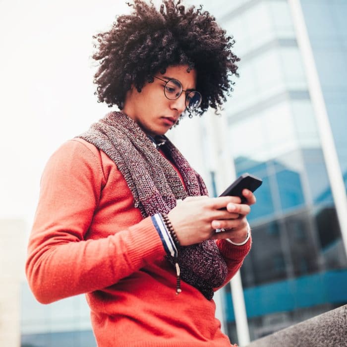 handsome curly man in stylish casual clothes using mobile phone