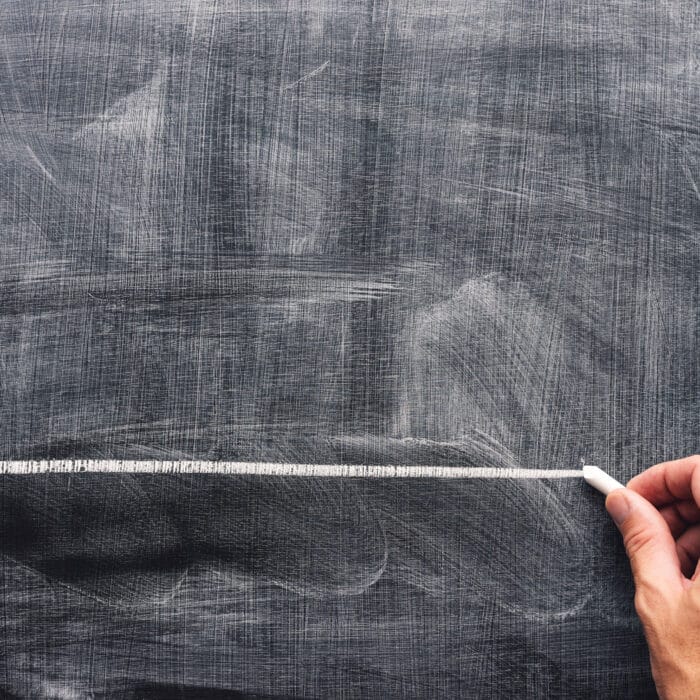 Hand underlining with chalk on school blackboard