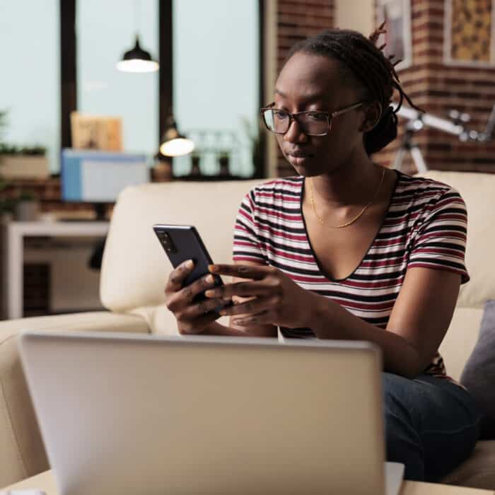 Young african american woman typing message on smartphone