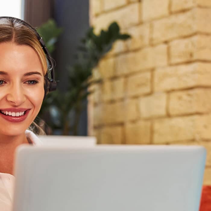 Charming business lady in headphones talking with business partner on laptop